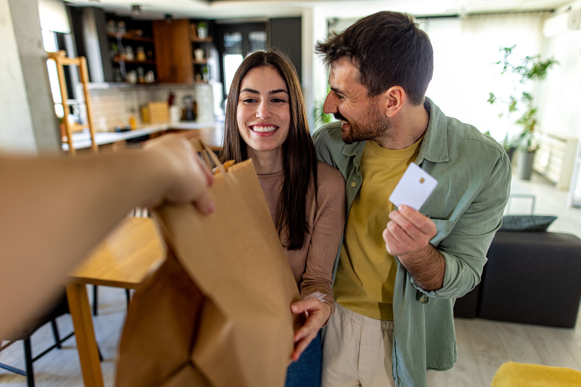Happy couple receiving grocery bag and paying with credit card at home